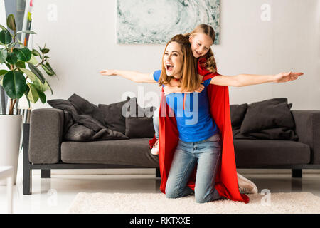 Tochter und Mutter in rote Mäntel lächelnd und Spielen zu Hause Stockfoto