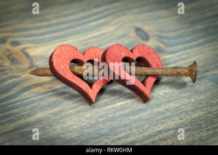 Zwei Holz- Herzen miteinander verbunden mit kleinen verrosteten Nagel. Schneiden Sie Holz- Herzen formen rot lackiert, in enger gesehen - bis auf Holzuntergrund mit Cop Stockfoto