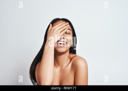 Gute Nachrichten Portrait von fröhlichen asiatische Frau mit langen Haaren die Hand auf ihren Kopf und Gefühl zufrieden, super Nachrichten. Positive Emotionen. Grauer Hintergrund Stockfoto