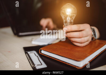 Hand der Frau mit einer Glühbirne für Buchhaltung und kreativ. Neue Ideen, Innovation und Inspiration Konzepte Stockfoto