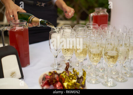 Barkeeper gießen Champagner oder Wein in die Gläser auf dem Tisch im Freien feierliche Zeremonie und Süßigkeiten Stockfoto