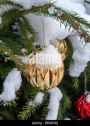Nahaufnahme von Schnee bedeckt Weihnachtskugel Dekorationen auf einen Weihnachtsbaum. Stockfoto
