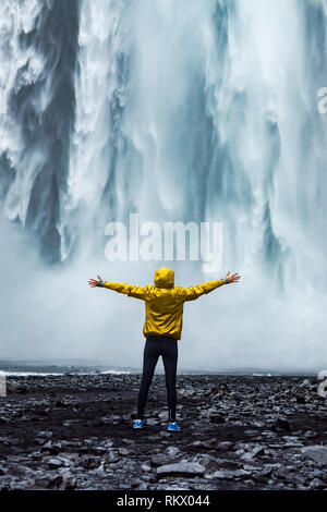 Eine Person admirnig die Schönheit der Skogafoss Wasserfall in Island entfernt Stockfoto