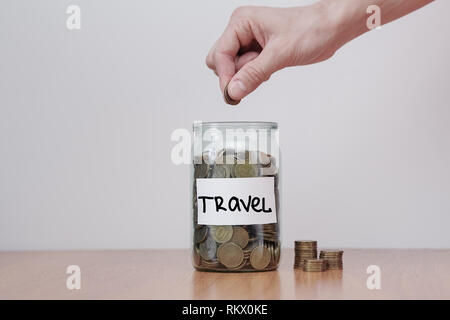 Verteilung der Einsparungen Konzept. Die Hand auf das Glas Münzen Geld Boxen mit Inschrift "Reisen" Stockfoto