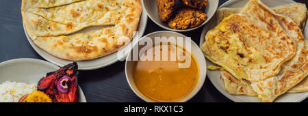 Sortierte indisches Essen auf dunklem Hintergrund. Gerichte und Vorspeisen der indischen Küche. Curry, Butter Huhn, Reis, Linsen, Paneer, Samosa, Naan Stockfoto