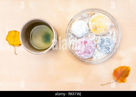 Grüner Tee Tasse und mochi Reiskuchen Japanischen daifuku Dessert wagashi bunte Blätter im Herbst auf dem Tisch Farbe und flache Ansicht von oben Stockfoto