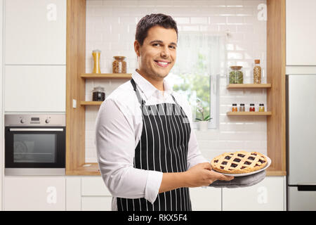 Junger Mann mit einer Torte in einer modernen Küche Stockfoto