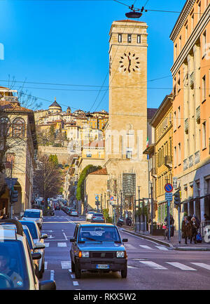 Turm des Palazzo delle Poste e Telegrafi mit die Citta Alta im Hintergrund. Blick von Largo Bortolo Belotti Straße. Bergamo, Lombardei, Italien. Stockfoto