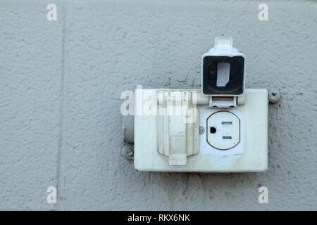 Alten rustikalen Nordamerikanischen Steckdose auf eine äußere graue Mauer Stockfoto