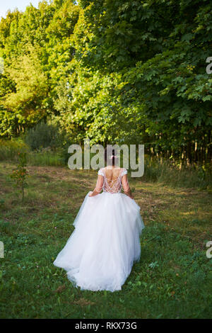 Junge Mädchen in einem weißen Kleid auf der Wiese. Frau in einem schönen langen Kleid in den Garten stellen. Stockfoto