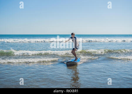 Junger Mann, Anfänger Surfer lernt Surfen auf einem Meer Schaum auf der Insel Bali Stockfoto