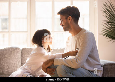 Kleine Tochter spielen Spiel als Arzt Spaß mit Papa Stockfoto