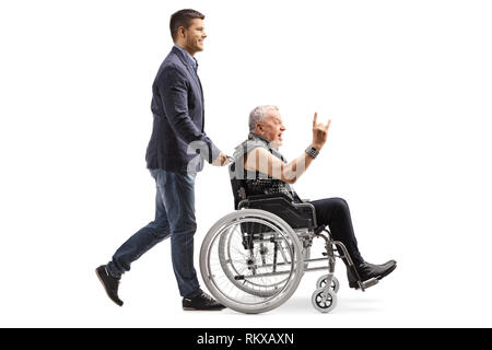 Volle Länge Profil Schoß eines jungen Mannes drückt ein Mann in Leder Weste einen Rock und Roll hand Zeichen in einem Rollstuhl auf weißem Hintergrund Stockfoto