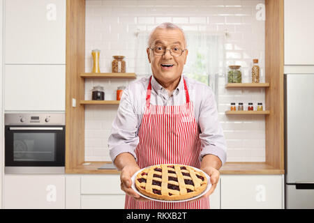 Reifen Mann hält einen frisch gebackenen Kuchen und stehen in einer Küche Stockfoto