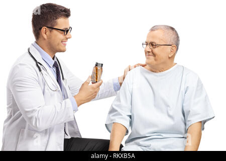 Arzt hält eine Flasche Pillen und ein Gespräch mit einem erwachsenen Patienten tragen einen Patientenkittel auf weißem Hintergrund Stockfoto