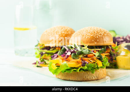 Leckere Burger aus frischen Sesam Brötchen und rohes Gemüse und junge Triebe blaues Licht Hintergrund. Gesunde Ernährung Stockfoto