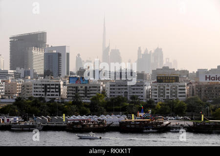 Downtown Dubai mit seinen hoch angehoben Türme einschließlich der höchsten, der Burj Khalifa, umgeben am späten Nachmittag Hitzeflimmern vom Dubai Creek in Stockfoto