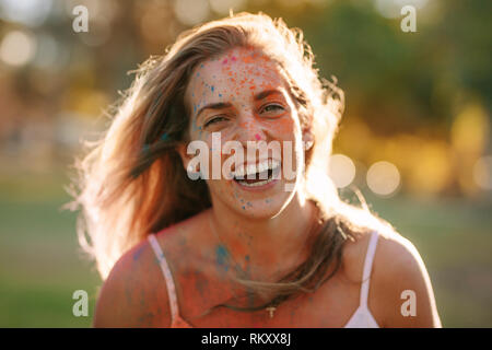 Frau mit Farben spritzte auf Ihren Körper lachen. Glückliche Frau Spaß holi Spielen im Freien. Stockfoto