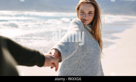 Frau genießen Wandern mit Freund an der Küste entlang. Glückliches Paar Walking am Strand halten sich an den Händen. Stockfoto