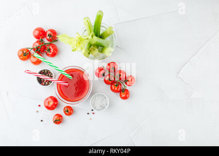 Glas leckeren Tomatensaft mit zwei gestreifte Trinkhalme, Stiele von frischen Sellerie, Salz, Pfeffer und frischen saftigen Kirschtomaten auf einem hellen Hintergrund. B Stockfoto