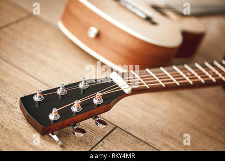 Tuning Sound. Nahaufnahme des Gitarrenhals mit Stimmschlüssel für die Anpassung der Gitarre Saiten liegen auf dem Holzboden. Musikinstrumente. Musik Equipment. Musik Shop Stockfoto