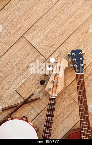 Blick von oben auf die Instrumente: Gitarren, Schlagzeug mit Stöcken liegen auf hellen Hintergrund. Music Studio. Musikinstrumente. Stockfoto