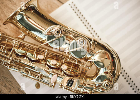 Die Freude der Sax. Blick von oben auf die schönen glänzenden Saxophon liegen auf Blätter für Noten und Holzboden. Musikinstrumente. Musik Equipment. Stockfoto