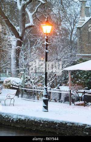 Straßenlaterne in Bourton auf dem Wasser am frühen Morgen Schnee. Bourton auf dem Wasser, Cotswolds, Gloucestershire, England Stockfoto