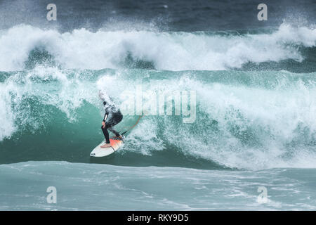 Ein Surfer auf einer Welle an Fistral Beach in Newquay in Cornwall. Stockfoto