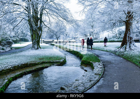 Die Menschen genießen einen Spaziergang im Schnee in Trenance Gärten in Newquay in Cornwall. Stockfoto