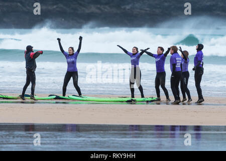 Unerfahrene surfer Aufwärmen mit ihrem Ausbilder zu Beginn einer surflektion am Fistral Beach in Newquay in Cornwall. Stockfoto