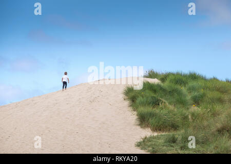 Ein Junge klettern auf einer Sanddüne an Crantock in Newquay in Cornwall. Stockfoto