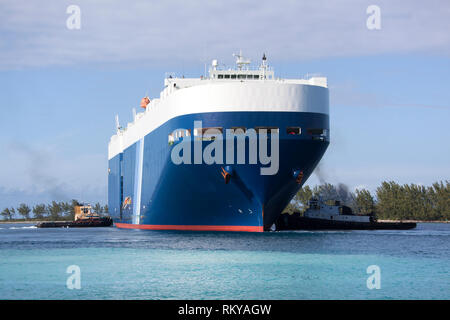 Zwei Schlepper schieben riesige Tanker, helfen zu manövrieren im Hafen von Nassau (Bahamas). Stockfoto