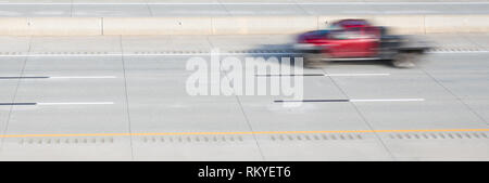 Ein roter Tieflader verschwommene Bewegung auf einer Autobahn mit Bewegung, während der Rest der Schuß im Fokus ist. Stockfoto