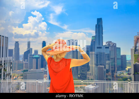 Lifestyle Frau mit breiten Hut genießt Panorama von einem der höchsten Wolkenkratzer über Singapur Chinatown. Luftaufnahme von Skyline Skyline. Kaukasische Stockfoto