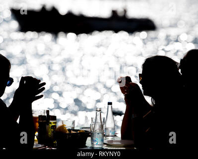 Touristen essen Fisch und Meeresfrüchte in einem Restaurant am Meer mit dem Mittelmeer. Stockfoto