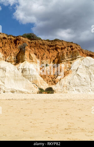 Hohe Klippen entlang den Strand Praia da Falésia und den Atlantik in Albufeira, Algarve, Portugal. Sonnigen Sommertag, blauer Himmel mit stürmischen Wolken. Stockfoto