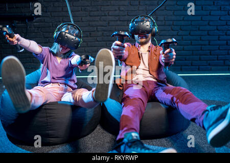 Der Mann und die Frau das Schießen mit Gamepads beim Spielen in der virtuellen Realität Mit VR-Headsets im Zimmer Stockfoto