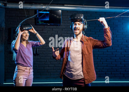 Glückliche Menschen gewinnen Virtual Reality Spiel stehend mit junge Frau im Zimmer Stockfoto