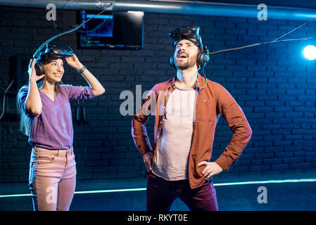 Glückliche Menschen gewinnen Virtual Reality Spiel stehend mit junge Frau im Zimmer Stockfoto