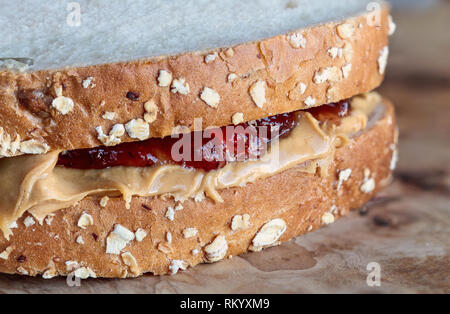 Hausgemachte Peanut Butter und Marmelade Sandwich auf Hafer Brot, über einen rustikalen Holzmöbeln Hintergrund für das Mittagessen bereit. Stockfoto