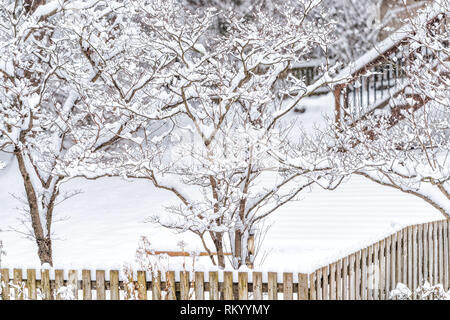 Holzzaun von Haus mit Rasen im weißen Schnee und Bäume Äste im Hinterhof von Haus Home mit niemand und deck Treppen abgedeckt Stockfoto