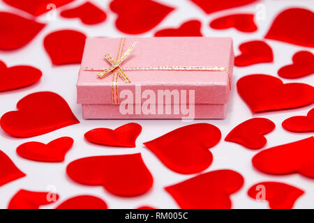 Ansicht von oben in einem rosafarbenen Geschenkbox von zerstreuten Herzen auf weißem Hintergrund umgeben. St. Valentines Tag Konzept Stockfoto