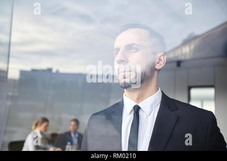 Ernster Mann durch Fenster Stockfoto