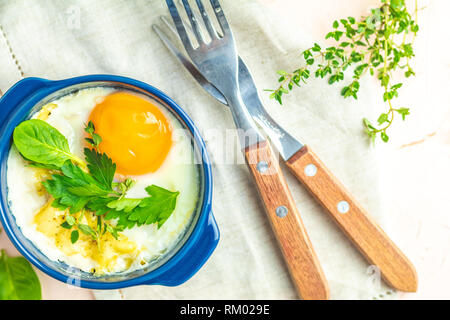 Eier kokot Cocotte französisches Frühstück. Gebackene Eier in blau Keramik Backformen. Portioniert Auflauf aus Gemüse und Eier im italienischen Stil. Stockfoto