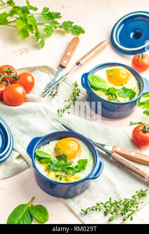 Eier kokot Cocotte französisches Frühstück. Gebackene Eier in blau Keramik Backformen. Portioniert Auflauf aus Gemüse und Eier im italienischen Stil. Stockfoto