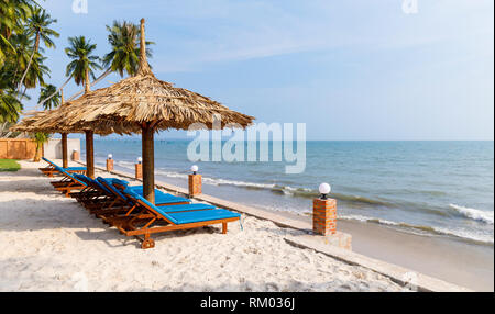 Liegestühle unter Sonnenschirmen im Waterside in Vietnam. Stockfoto