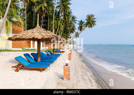 Liegestühle unter Sonnenschirmen im Waterside in Vietnam. Stockfoto