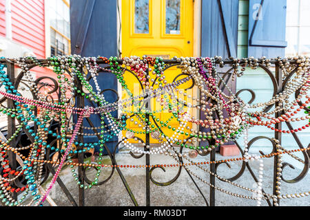 New Orleans, USA - 23. April 2018: Nahaufnahme von Mardi Gras Perlen am Zaun durch farbenfrohe Gebäude Haus Eingang und niemand auf Bürgersteig Stockfoto