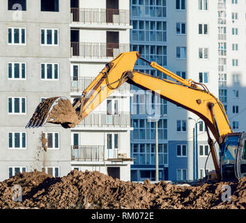 Gelber Bagger graben den Boden an der Baustelle. Stockfoto